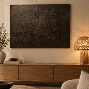Erdung I – schwarze Strukturkunst über einem Holz-Sideboard im warmen Wohnzimmer